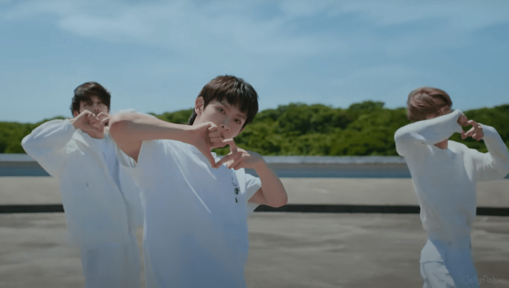 Cena do MV de "Badder Love" do álbum RIDE or DIE com os membros do EVNNE formando coração com as mãos em parte da coreografia