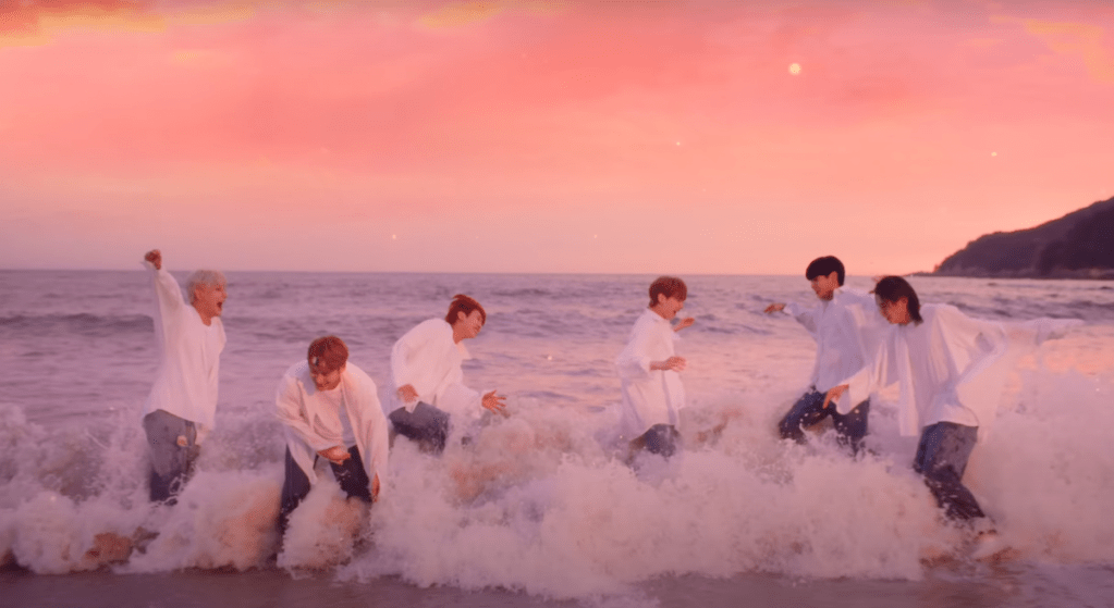 Cena do MV de Vanilla Choco Shake do álbum Sweet Tape do WAKER com todos os membros brincando com as ondas do mar