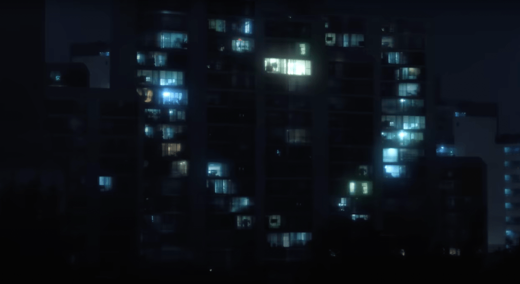 Cena do MV de "XO (Only If You Say Yes)" do álbum ROMANCE : UNTOLD do ENHYPEN com luzes das janelas de um prédio à noite, formando um coração