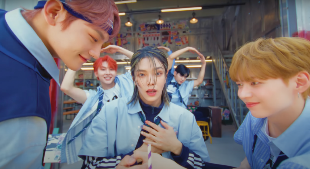 Cena do MV de Vanilla Choco Shake do álbum Sweet Tape do WAKER com todos os membros fazendo pose de coração com as mãos