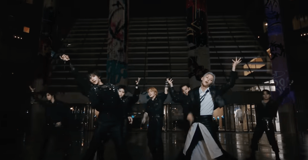 Cena do MV de "Chk Chk Boom" do álbum ATE com todos os membros do Stray Kids dançando em um cenário com fundo preto