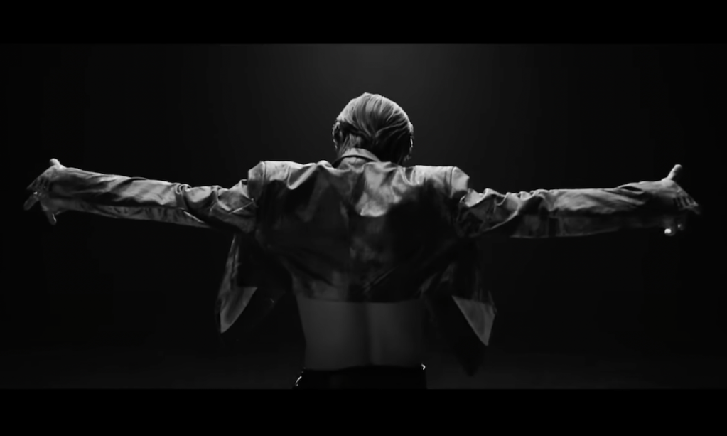Cena do MV de "Sexy In The Air" do álbum ETERNAL do Taemin, com ele de costas em um fundo todo preto
