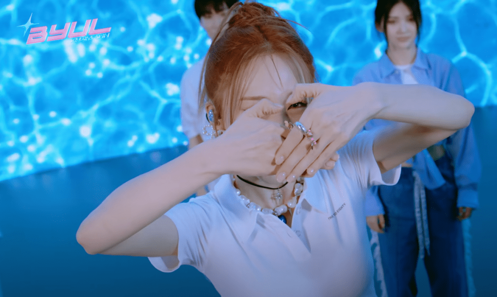 Cena do MV de "Is This Love?" do álbum Starlit of Twinkle da Moon Byul com sinal de coração feito com as mãos