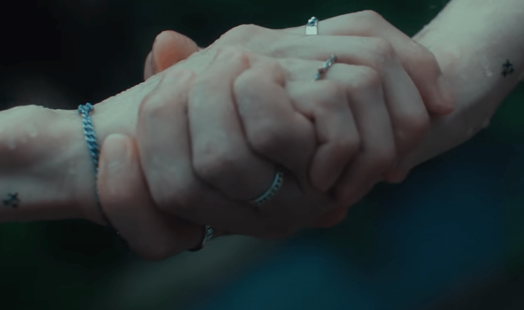 Cena do MV de "Rains in Heaven", single em inglês do NCT Dream com close em mãos dadas, simbolizando apoio e conforto