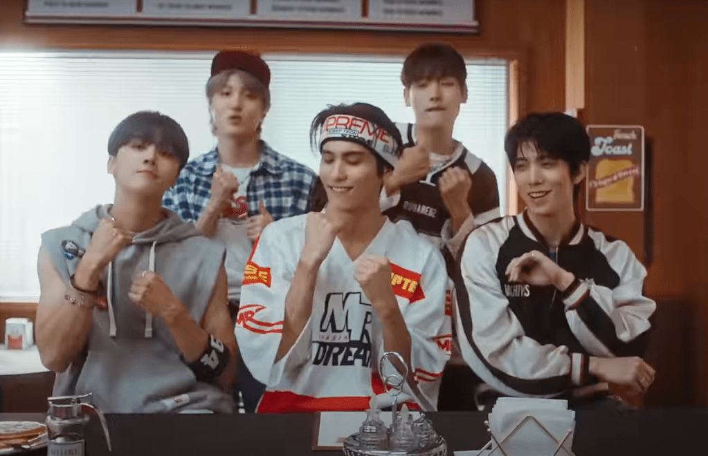 Cena do MV de "Don't Worry, Be Happy" do SF9 com o álbum Fantasy, mostrando Cha Ni, Hwi Young, In Seong, Yoo Tae Yang e Young Bin mexendo o corpo enquanto estão sentados