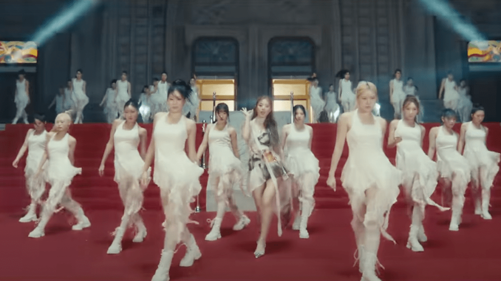 Cena do MV de "Run Away" do álbum abouTZU, marcando o solo de Tzuyu, que aparece dançando em um tapete vermelho com várias dançarinas para acompanhar