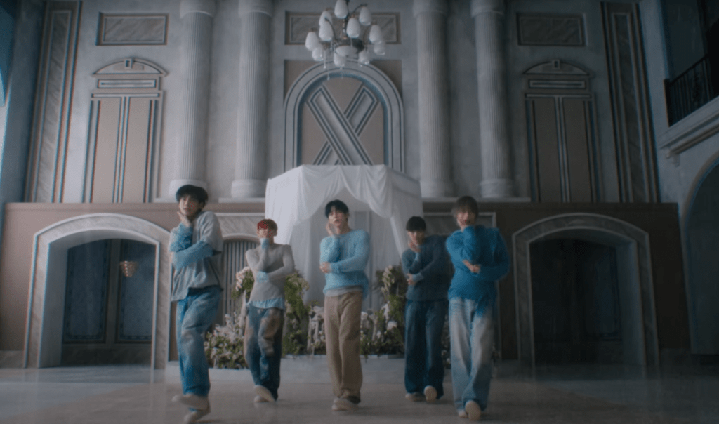 Cena do MV de "Over the Moon" do álbum The Star Chapter: SANCTUARY com todos os membros do TXT dançando em um cenário claro
