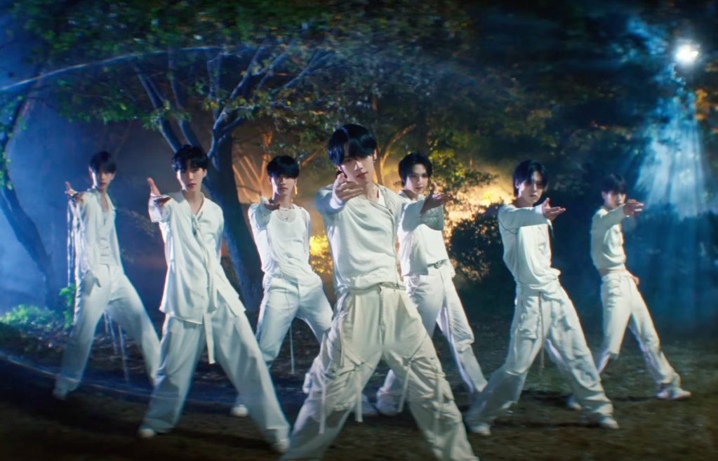 Cena do MV de "UNIVERSE" do álbum Youth Chapter 2: YOUTH DEFICIENCY do EPEX com todos os membros na floresta em uma cena de dança