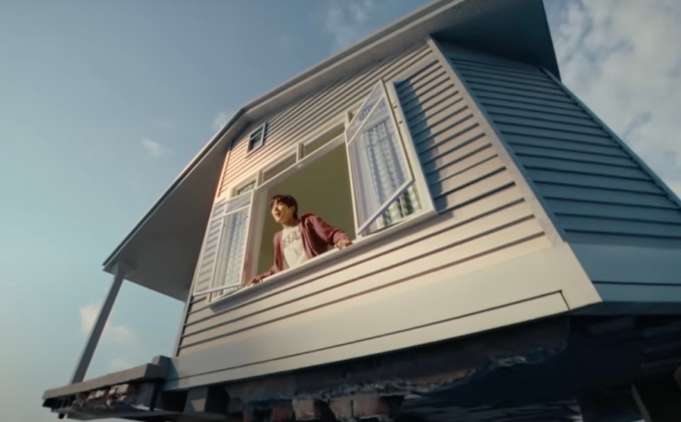 Cena do MV de "Sweet Dreams" com J-Hope na janela em uma casa flutuante