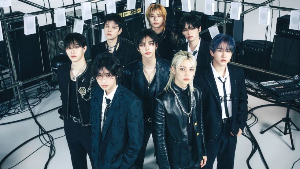 Stray Kids com todos os membros de preto em um cenário com equipamentos de som