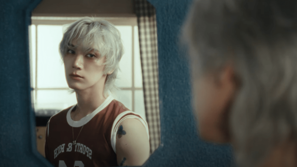 Cena do MV de STUNNER onde Ten aparece de costas para a câmera, com sua imagem refletida no espelho