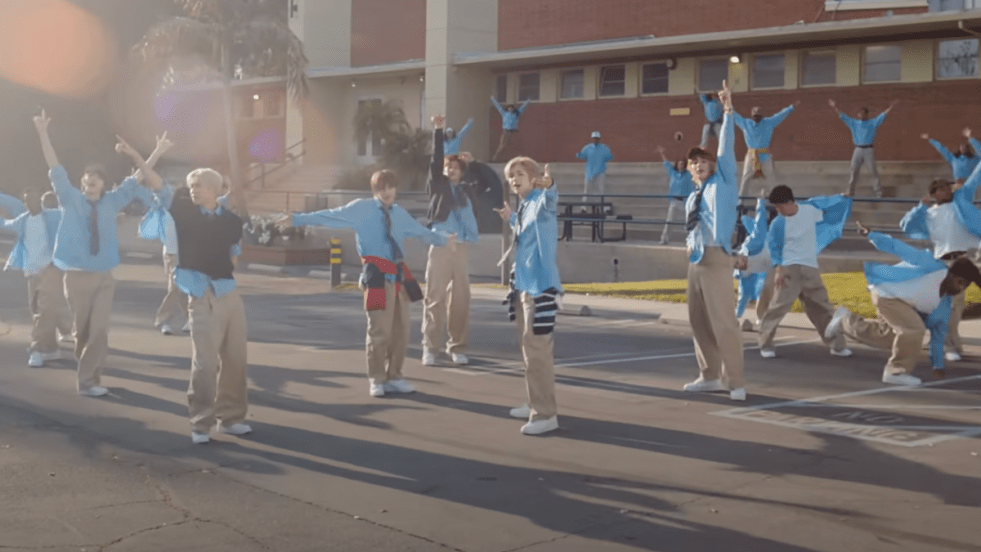 Cena do MV de "Fly Up" do álbum ODYSSEY do RIIZE com todos os membros ao ar livre, vestindo uniformes