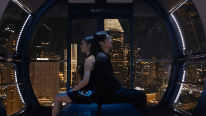 Cena do MV de "Don't Say You Love Me" do álbum Echo com Jin (BTS) e a atriz Shin Se-kyung sentados um de costas para o outro com o cenário noturno da cidade ao fundo