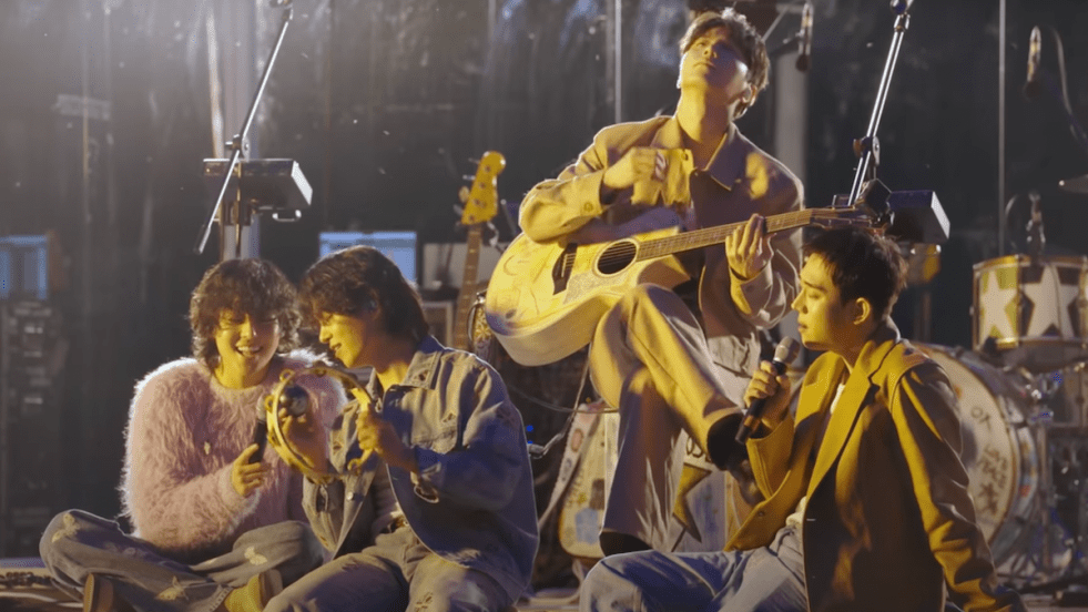 Cena do vídeo especial de performance do The Rose para o lançamento do álbum WRLD. Woosung, Hajoon, Jaehyung e Dojoon estão sentados no palco em um lugar cercado pela natureza durante a noite