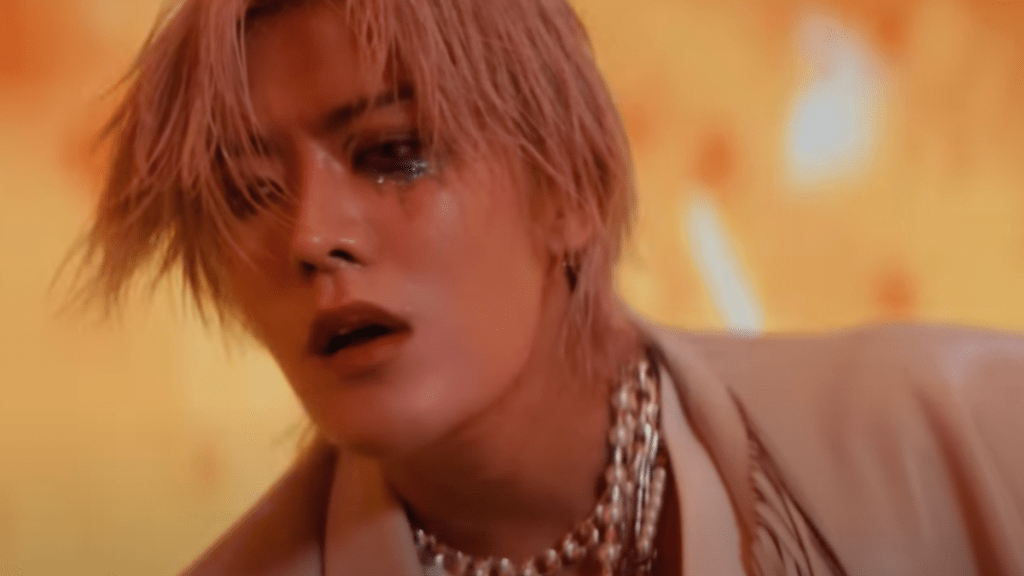 Cena do MV de TWISTED PARADISE do Yuta [NCT]. Na imagem, com fundo amarelo dourado, close no rosto de Yuta