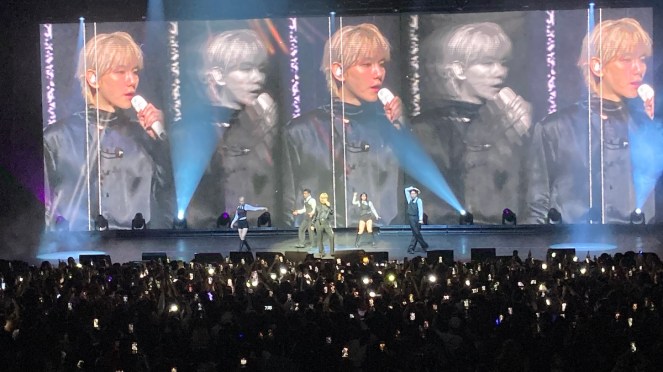 Baekhyun no Brasil durante show do tour Reverie em São Paulo. No palco, ele canta vestido de preto ao laado de seus dançarinos