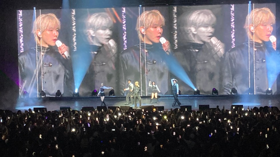 Baekhyun no Brasil durante show do tour Reverie em São Paulo. No palco, ele canta vestido de preto ao laado de seus dançarinos