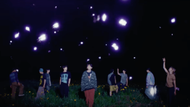 Cena do MV de "Set Net G0?!" do álbum Dare to Crave do CRAVITY. Todos os membros estão ao ar livre de noite, com brilhos roxos ao redor deles