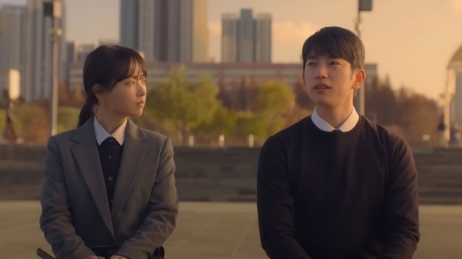 Cena do K-Drama Our Unwritten Seul com Mi-Ji (Park Bo-Young) e Ho-Su (Jinyoung) sentados no banco de um parque