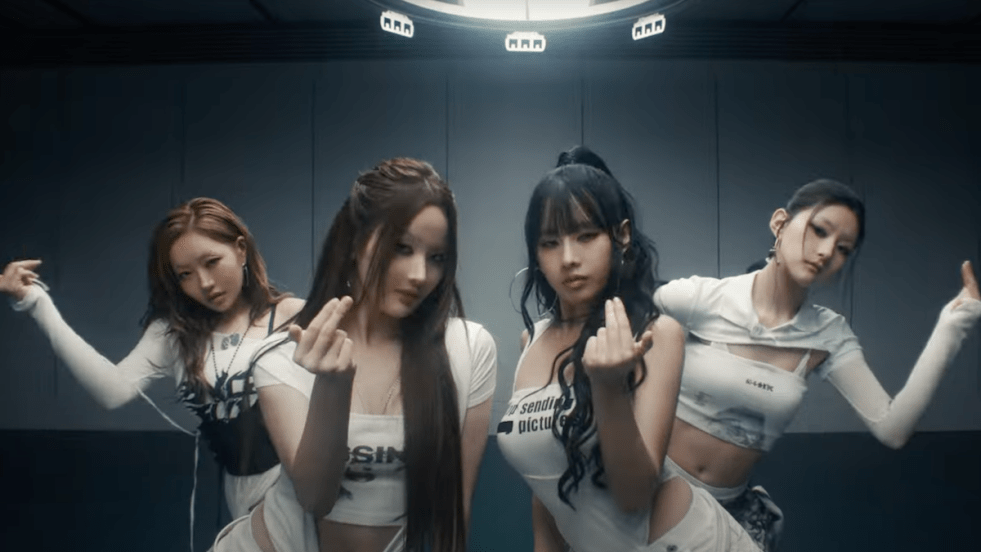 Cena do MV de "Lips Hips Kiss" do álbum 224 do KISS OF LIFE. Enquanto dançam vestidas de branco e preto, as meninas fazem um sinal com as mãos para se aproximar