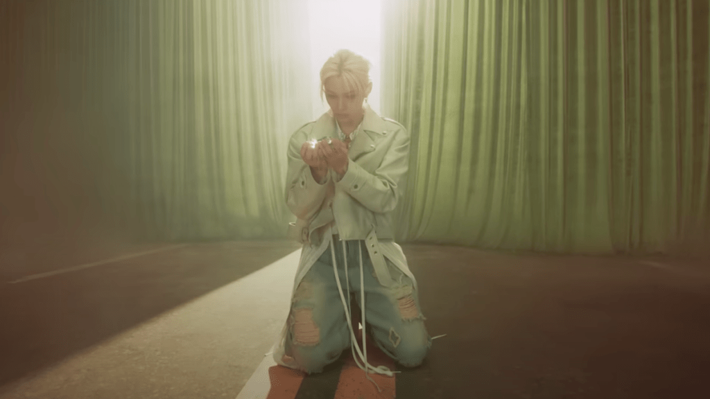 Cena do MV de Hollow com Felix do Stray Kids com a luz nas mãos