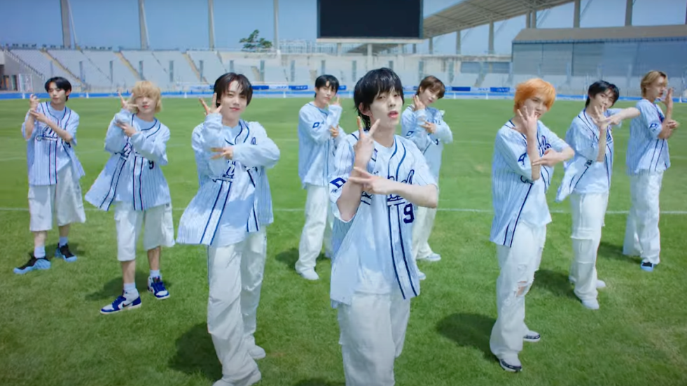 Cena do MV de Rendezvous do álbum de debut do AHOF: WHO WE ARE. Os 9 membros vestem roupas que remetem aos uniformes de beisebol, enquanto dançam em um estádio