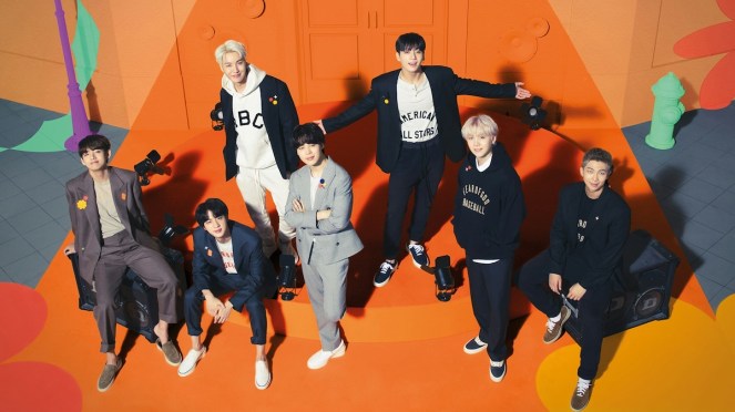 Imagem com todos os membros do BTS sorrindo em um cenário com o fundo laranja para o álbum Permission to Dance on Stage - Live