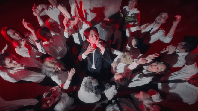 Cena do MV de "ANIMALS" do álbum PERCENT onde Onew aparece cantando cercado por uma multidão