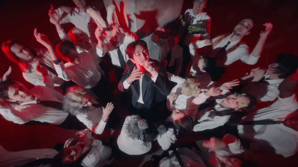 Cena do MV de "ANIMALS" do álbum PERCENT onde Onew aparece cantando cercado por uma multidão