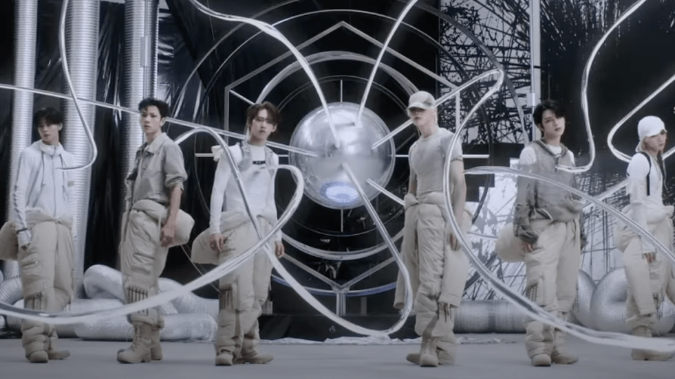 Membros do SEVENTOEIGHT em cena final do MV de seu single de estreia "DRIP&DROP", todos vestidos de branco em um cenário futurista