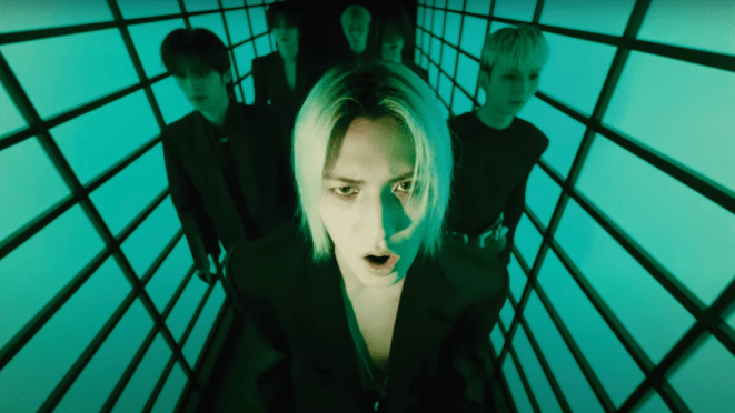 Cena do MV do single “FiRE (My Sweet Misery)” com todos os membros do Xdinary Heroes em um corredor escuro com luz verde. Jooyeon na frente