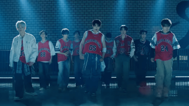 Cena do MV de "SLAM DUNK" do ZEROBASEONE com todos os membros no clima do basquete em um cenário com baixa iluminação