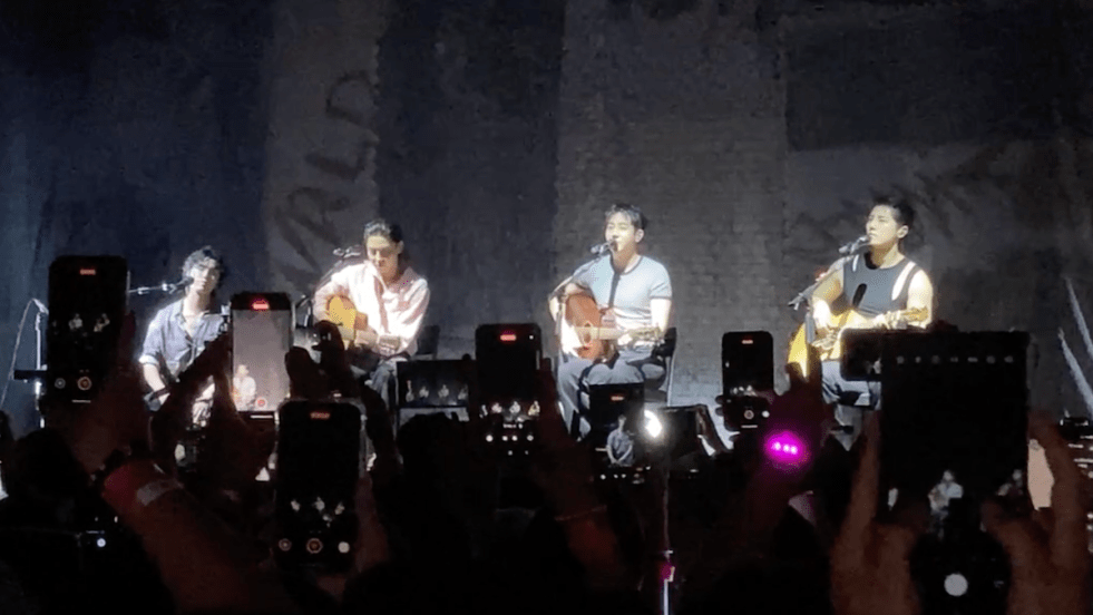 The Rose no Brasil: Hajoon, Taegyeom, Woosung e Dojoon sentados enquanto tocam no palco do Vibra SP