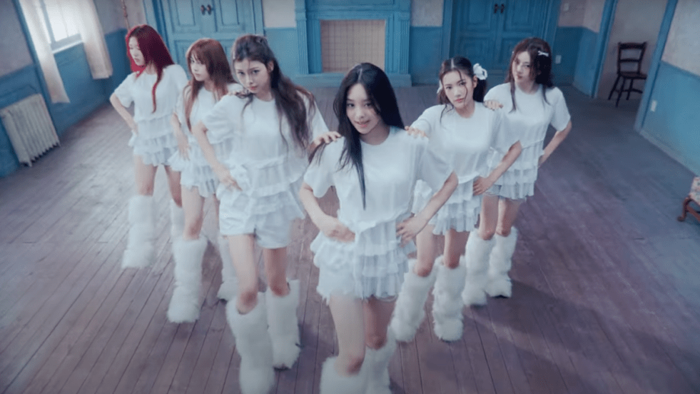 Cena do MV de "Plot Twist", que marca o debut oficial do AtHeart. Na imagem, todas as integrantes, menos Aurora, dançam de branco