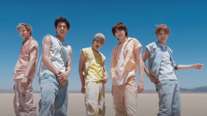 Cena do MV de "What You Want", single de debut do CORTIS com os cinco membros posando para a câmera na praia em um dia de céu azul