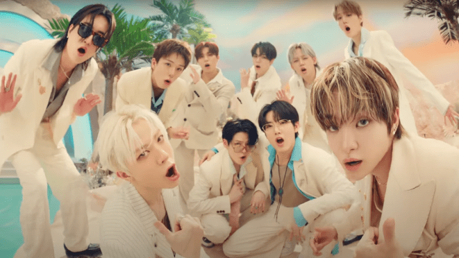 Cena do MV de "PARADISE" do álbum LOVE PULSE do TREASURE, com todos os integrantes em um cenário praiano, usando roupas claras.