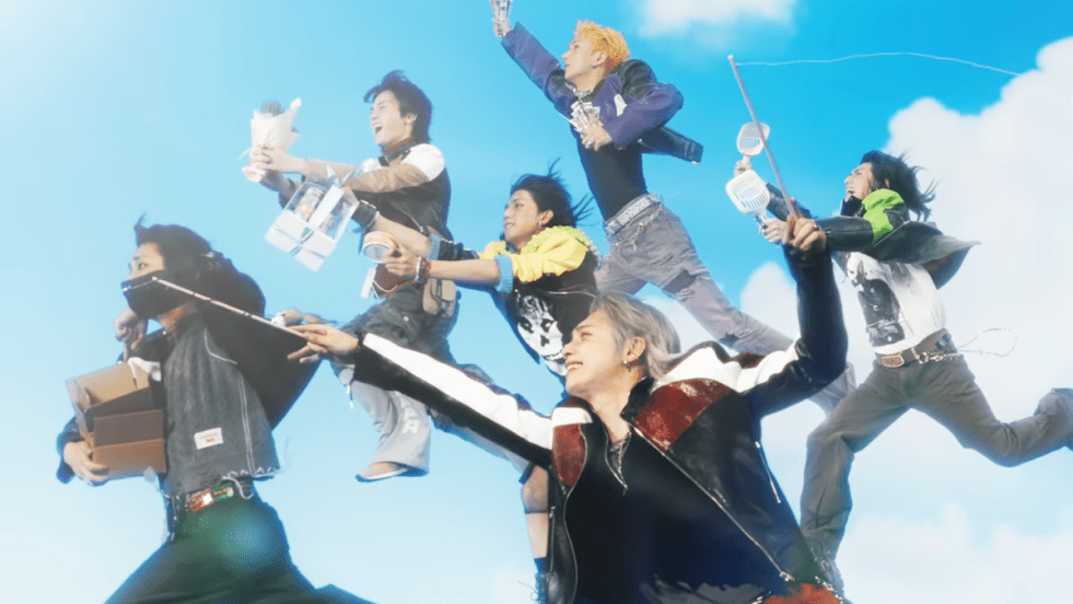 Cena do MV de "ICU" do álbum LXVE to DEATH do Xdinary Heroes, com todos os membros da banda "voando" alto no céu