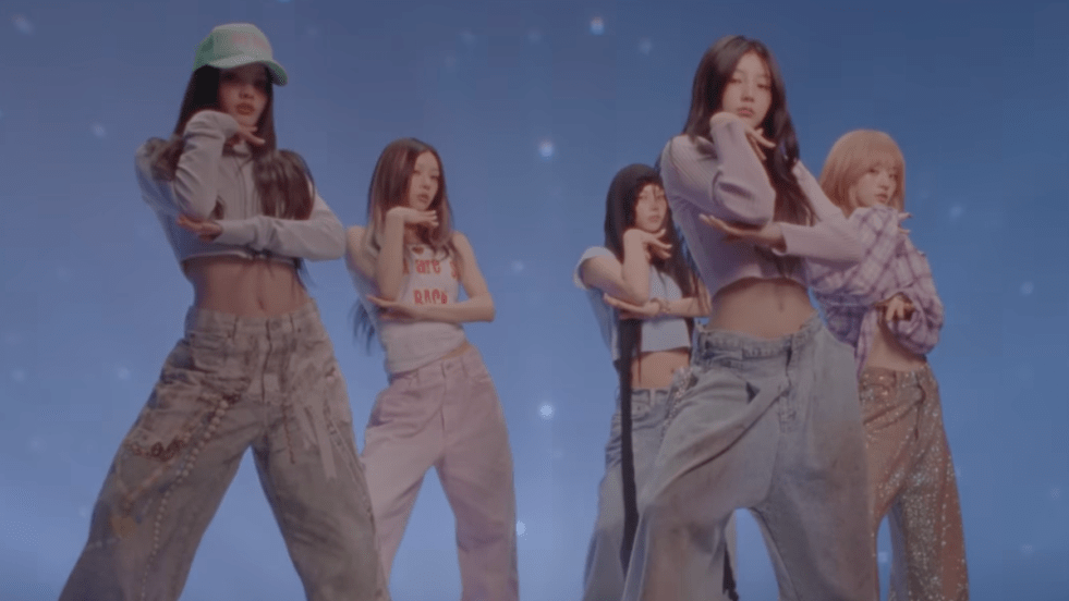 Cena do MV de "Not Cute Anymore" com todas as meninas do ILLIT em pose, uma das mãos no queixo