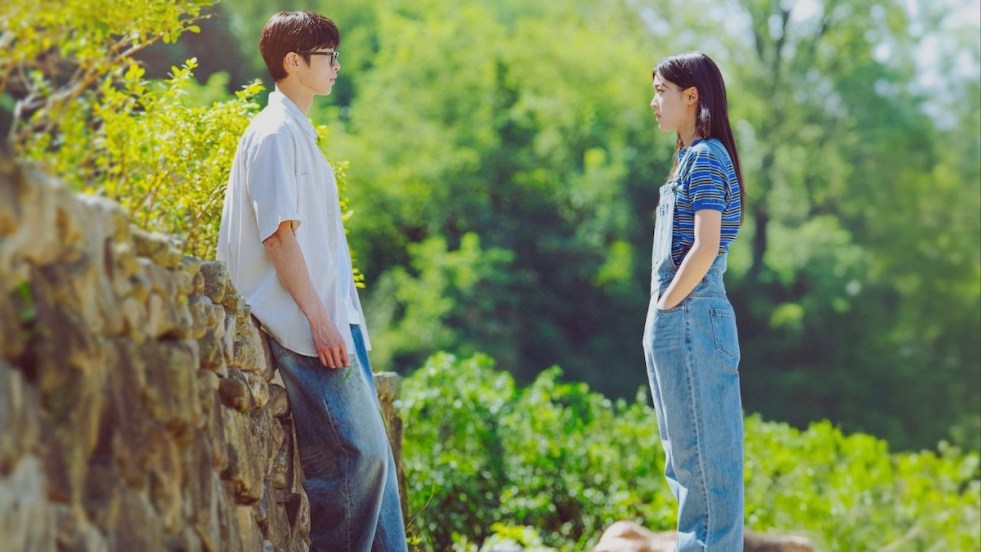 Imagem do K-Drama Last Summer em uma paisagem cheia de verde com os protagonistas Lee Jae-Wook (Baek Do-Ha), Choi Sung-Eun (Song Ha-Kyeong) frente a frente, olhando um para o outro