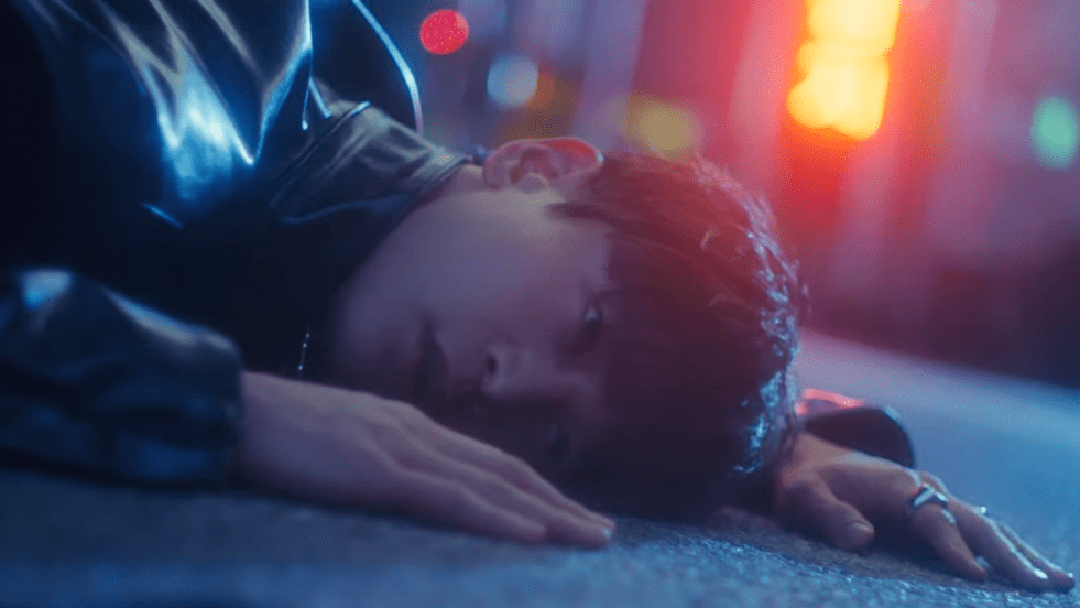 Cena do MV de "TEMPO" com Minho do SHINee deitado no chão, close no seu rosto