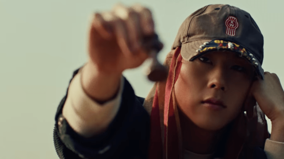 Review do álbum 光 (INSANITY): cena do MV de "STING" com Joohoney (주헌) do Monsta X (몬스타엑스) segurando uma peça de xadrez enquanto olha para a tela