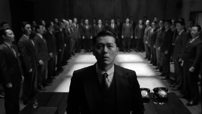 Review do K-Drama Made in Korea: Baek Ki-Tae (Hyun Bin) cercado por colegas da KCIA em uma imagem em preto e branco