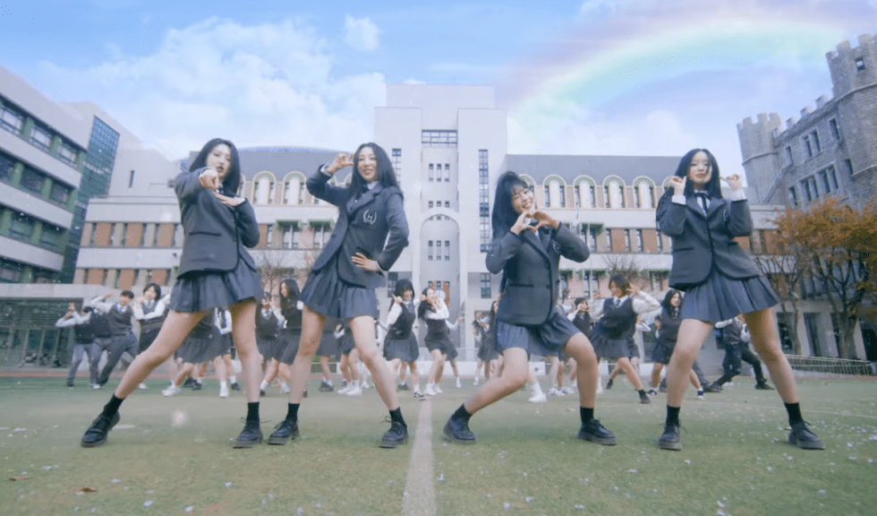 Review do álbum LOVECHAPTER do H1-KEY: cena do MV de "To. My First Love" com Hwiseo, Riina, Seoi e Yel no pátio de uma escola em poses fofinhas e divertidas enquanto dançam