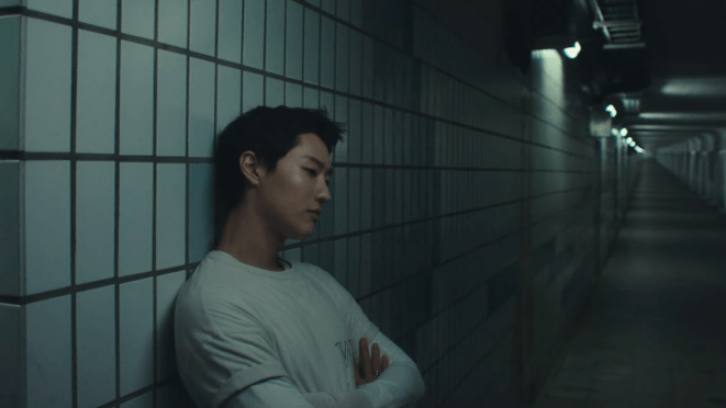 Review do álbum Archive. 1 do WOODZ: cena do MV de "Human Extinction" em um corredor escuro e ele encostado, com os braços cruzados e pensativo, na parede