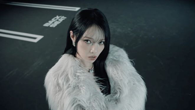 Review do álbum UNVEIL da Somin [KARD]: cena do MV de "Backseat" com ela olhando para a câmera de braços cruzados