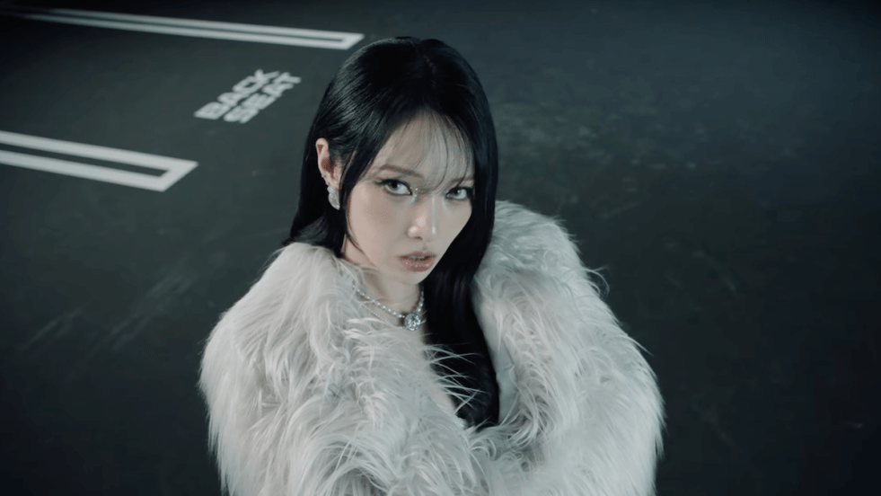 Review do álbum UNVEIL da Somin [KARD]: cena do MV de "Backseat" com ela olhando para a câmera de braços cruzados