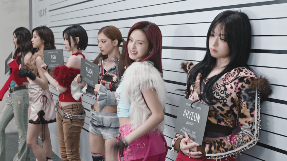 Review do álbum CHOOM do BABYMONSTER: cena do MV da title com as meninas em um cenário que simula quando a polícia coloca suspeitos de um crime lado a lado para fotos